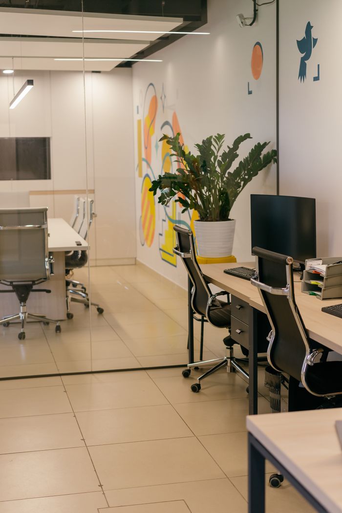 Un intérieur de bureau spacieux et contemporain, avec des cloisons vitrées, du mobilier élégant et des œuvres murales aux couleurs vives.